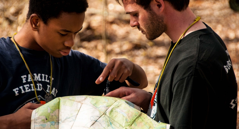 Two people people examine a map that one of them holds.